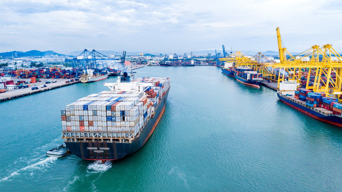 Cargo containers ship with logistics transportation pulling into harbor from sea